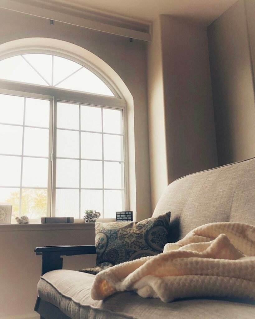 Cozy apartment corner with couch and warm blanket by window