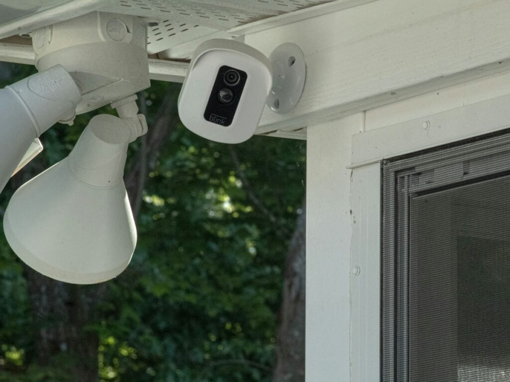 White outdoor security camera mounted near a door